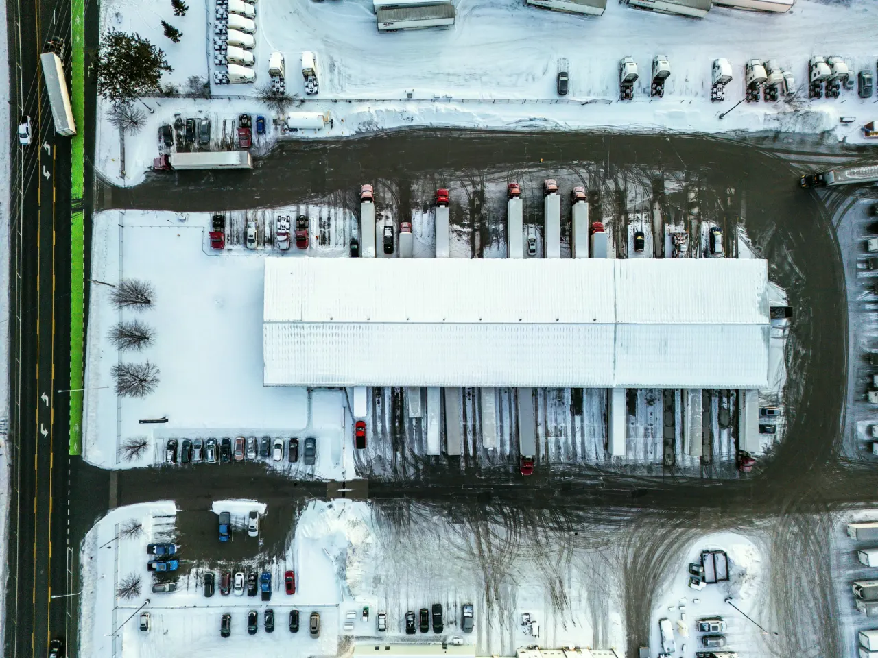 Aerial view of a snowy warehouse with trucks at the loading docks